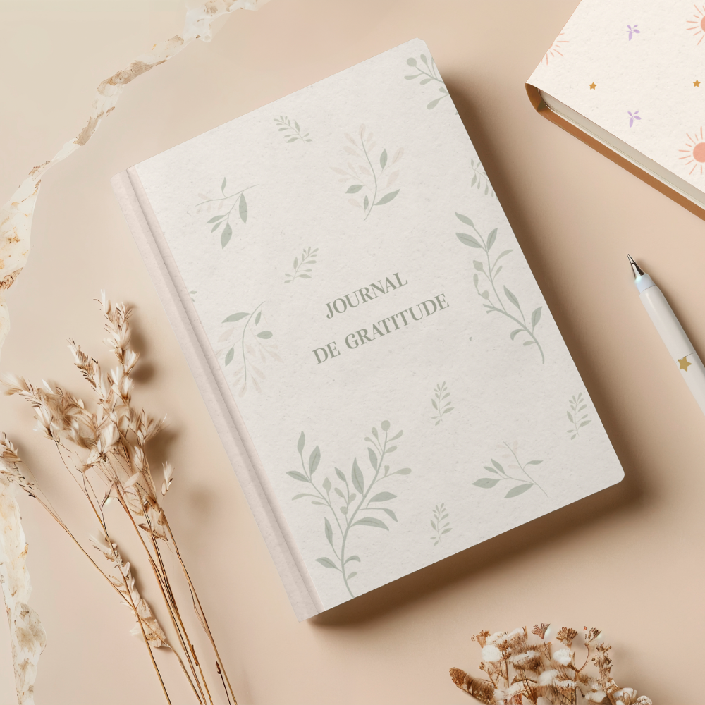 Journal de gratitude posé sur une table avec fleurs séchées, illustrant un design de motifs floraux pour packaging holistique et papeterie.